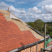 Red clay roof tiles being laid on a residential property in northwest London.